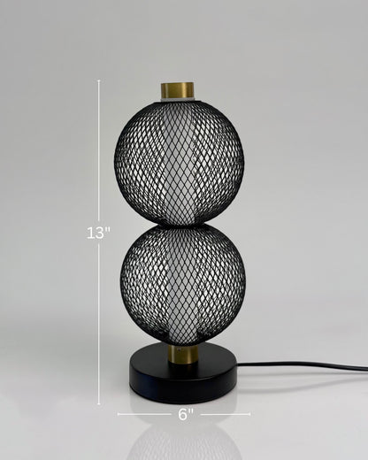 High Objects Celeste Duo Mesh Table Lamp with stacked spherical black mesh shades and brushed gold accents on a black base.