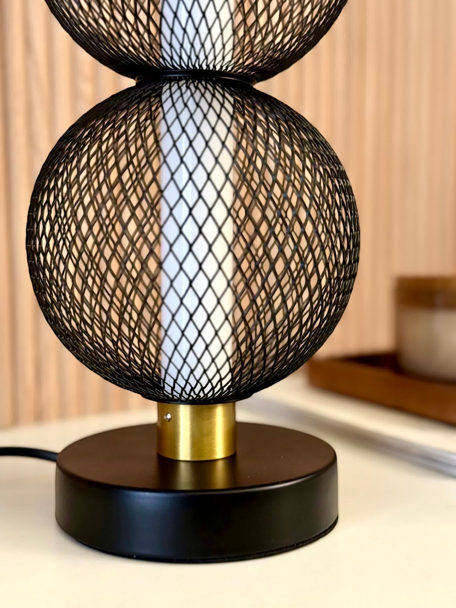 High Objects Celeste Duo Mesh Table Lamp with stacked black mesh spheres and brushed gold accents on a black base.