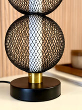 High Objects Celeste Duo Mesh Table Lamp with stacked black mesh spheres and brushed gold accents on a black base.