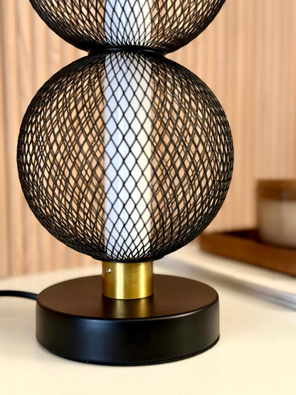 High Objects Celeste Duo Mesh Table Lamp with stacked black mesh spheres and brushed gold accents on a black base.