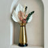 High Objects Celestia Vase: gold tapered vase with flared rim, cord detail, and black base, holding a dried floral arrangement.
