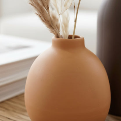 High Objects set of 3 ceramic vases in terracotta, dark brown, and cream, holding dried flowers and white blooms.