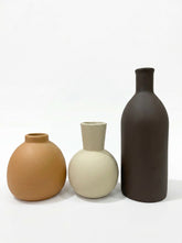 Set of three ceramic vases in brown, tan, and cream, featuring minimalist rounded and bottle shapes.