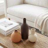 High Objects set of 3 ceramic vases in terracotta, dark brown, and cream, holding dried flowers and white blooms.