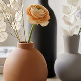 High Objects terracotta, grey, and black ceramic vases with dried flowers and a single orange ranunculus.