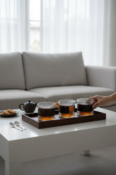 High Objects CINDER set of 4 amber glass cups with textured surface and matte sleeves filled with tea.