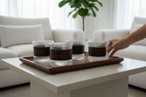 High Objects CINDER™ set of 4 amber glass cups with textured base and matte brown sleeves on a wooden tray.