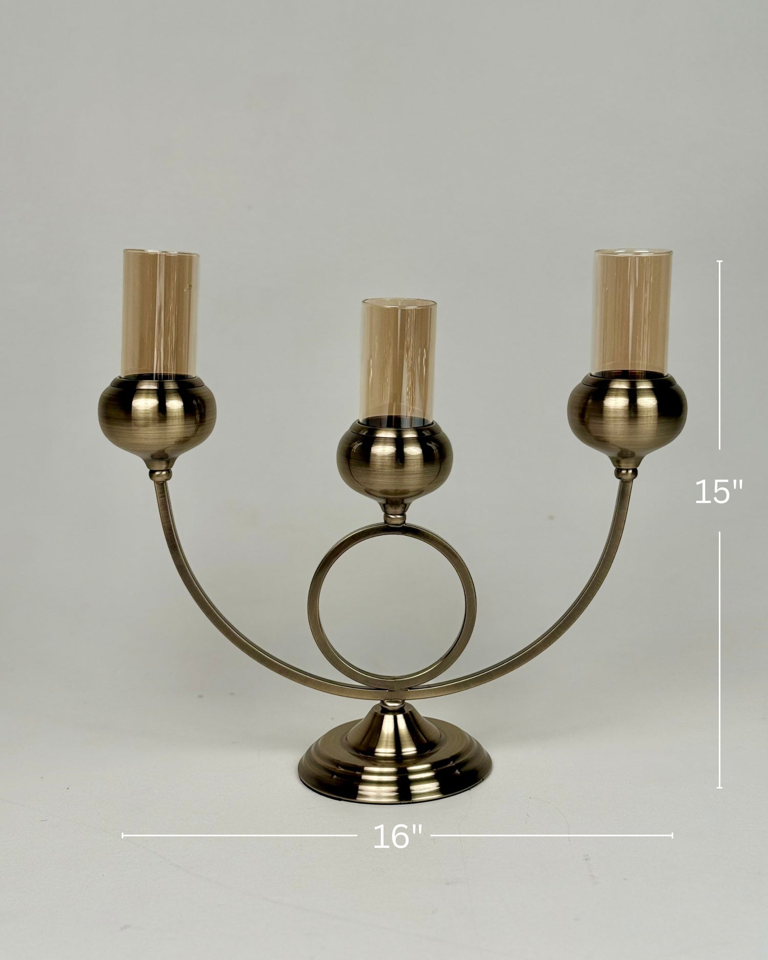High Objects Circa Arc Triple Candle Stand in antique brass with amber glass shades. Arched design with central ring.
