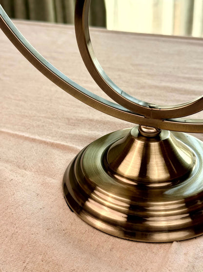 High Objects Circa Arc Triple Candle Stand in antique brass finish with a curved metal frame and pedestal base.