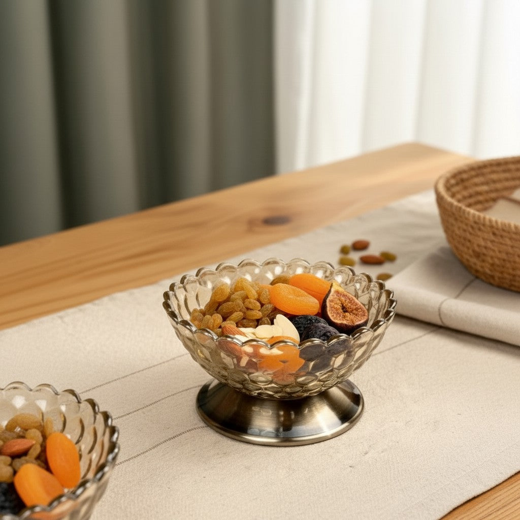 High Objects Crystal Bloom Accent Bowl, a textured glass bowl with scalloped rim on a metallic pedestal base, filled with dried fruits and nuts.