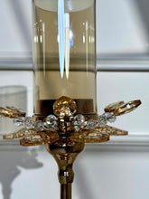 High Objects Crystal Bloom candle stand with amber glass hurricane and crystal petal accents. Elegant gold finish.