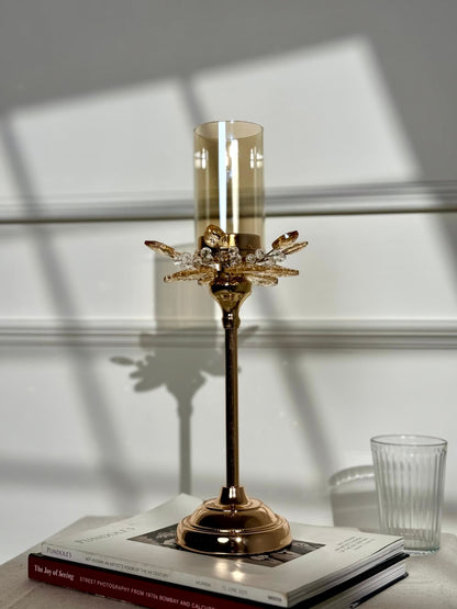 High Objects Crystal Bloom candle stand with amber glass hurricane and crystal petal accents on a rose gold base.