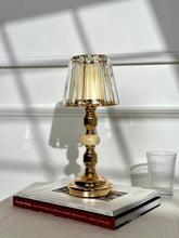 High Objects Crystal Belle candle stand with faceted glass shade and gold pedestal stem, on books.