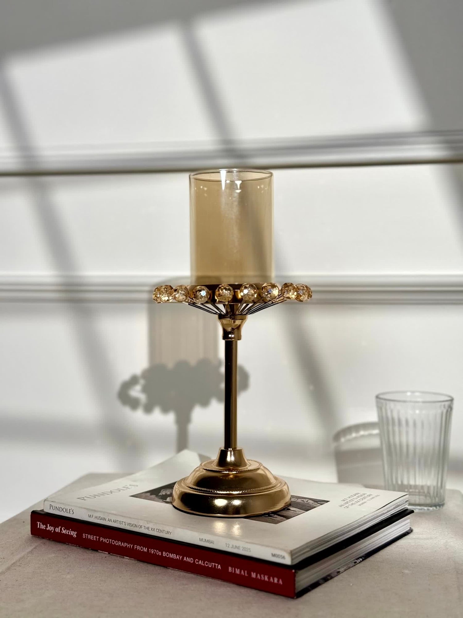High Objects gold candle stand with amber glass holder and crystal halo detail. Elegant pedestal base.
