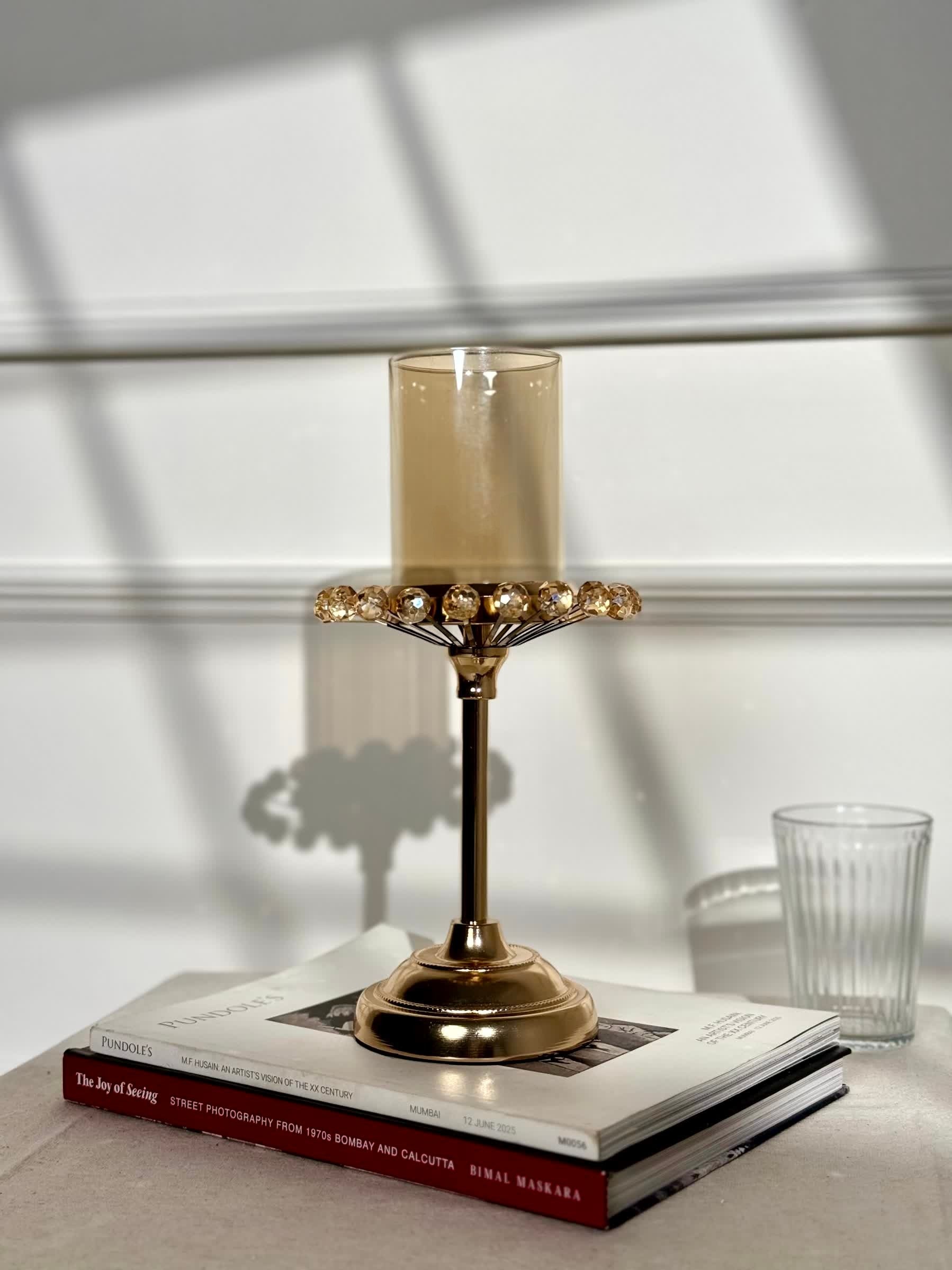 High Objects gold candle stand with amber glass holder and crystal halo detail. Elegant pedestal base.