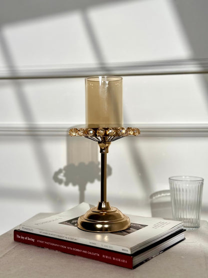 High Objects gold candle stand with amber glass holder and crystal halo detail. Elegant pedestal base.