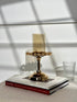 High Objects gold candle stand with crystal halo detail and pedestal base, on stacked books.