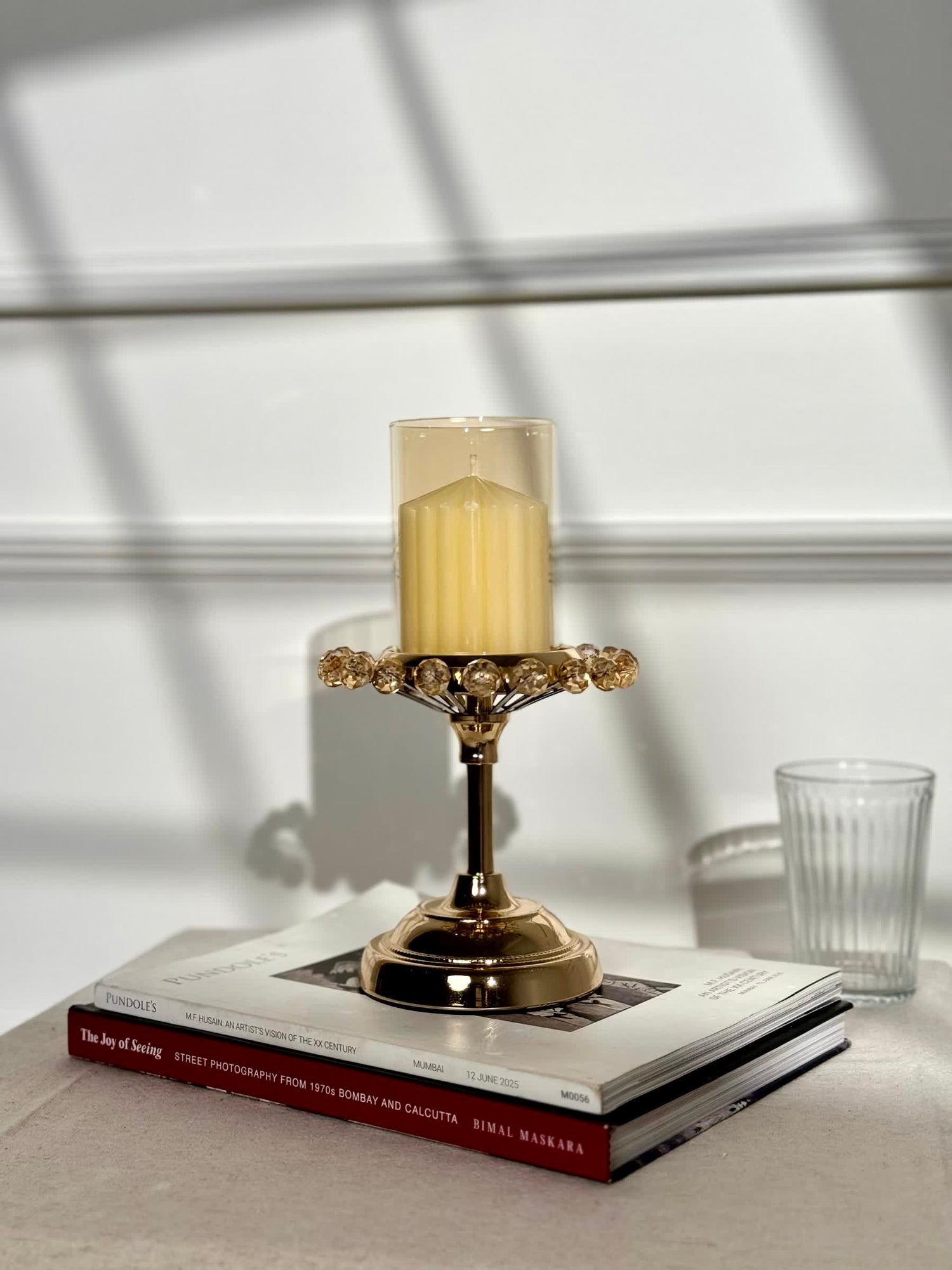 High Objects gold candle stand with crystal halo and tinted glass holder, topped with a yellow pillar candle.