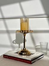 High Objects gold metal candle stand with amber glass shade and crystal accents, topped with a gold candle.