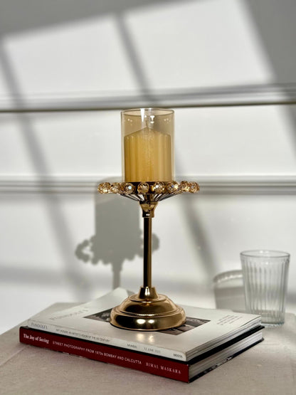 High Objects gold metal candle stand with amber glass shade and crystal accents, topped with a gold candle.