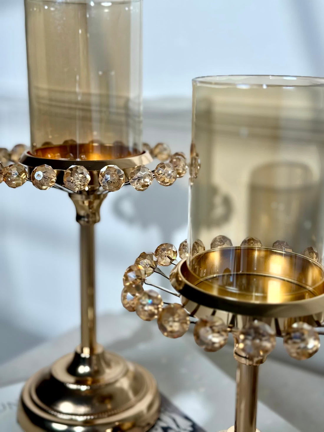 High Objects Crystal Halo Candle Stand Set with amber glass and gold metal base, adorned with crystal droplets.