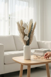 High Objects Maison Éclat dried botanical arrangement with cotton bolls, eucalyptus, and grasses in a white ceramic vase.