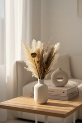 High Objects Aure Still dried botanical arrangement with pampas, bunny tails, and seed pods in a matte white ceramic vase.