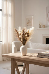 High Objects Aure Still dried botanical arrangement with pampas, bunny tails, and seed pods in a matte cream ceramic vase.