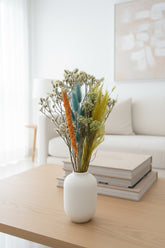 High Objects dried flower arrangement with golden yellow, teal, and orange botanicals in a white vase.