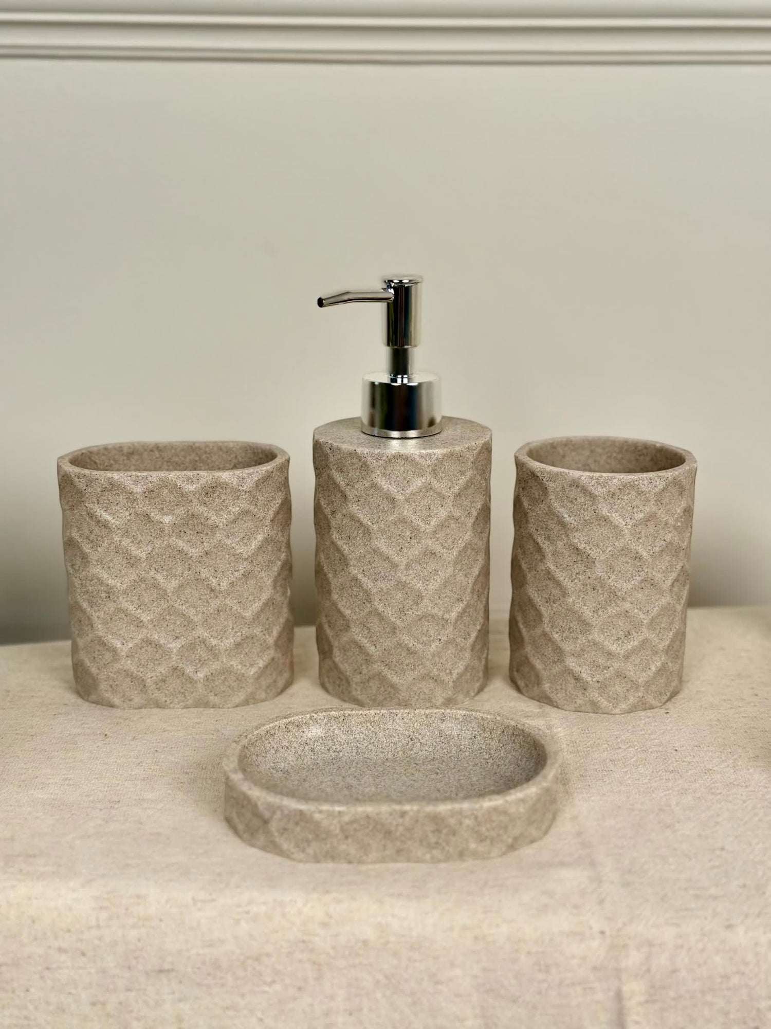 High Objects Dunecraft Bathroom Accessory Set in beige stone texture with geometric pattern. Includes soap dispenser, toothbrush holder, cup, and soap dish.