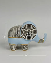High Objects Elysian Trunk Figurine, a soft blue polyresin elephant with black and gold geometric patterns on its body and ears.