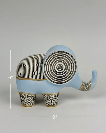 High Objects Elysian Trunk Figurine, a soft blue polyresin elephant with black and gold geometric patterns on its body and ears.