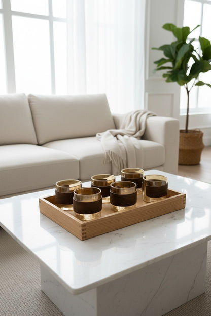 High Objects EMBERFORM glass cup set of 6, amber-tinted glass with wooden grip sleeves, on a wooden tray.