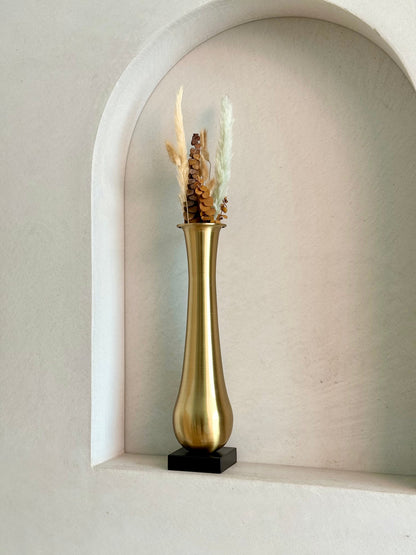 High Objects Eterna Gold Vase with dried pampas grass and pinecones, featuring a sleek silhouette and black square base.