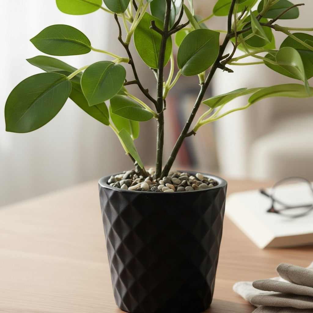 High Objects faux ficus plant in a black geometric pot with green leaves, on a wooden table with a book and glasses.