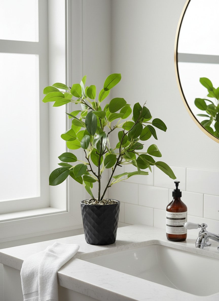 High Objects faux plant with vibrant green leaves in a textured black pot, styled on a wooden table with a book and mug.