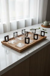 High Objects AXISFORM™ set of 6 clear glass square cups with dark geometric handles on a wooden tray.