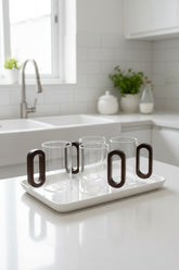 High Objects OBLIQ glass cups with dark wood handles, set of 4, on a white tray in a modern kitchen.