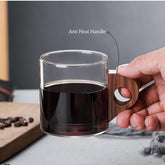 High Objects EchoBrew glass cup with anti-heat wooden handle, filled with dark liquid.