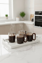 High Objects OBLIQ glass cups with dark wood handles, set of 4, filled with steaming coffee on a white tray.