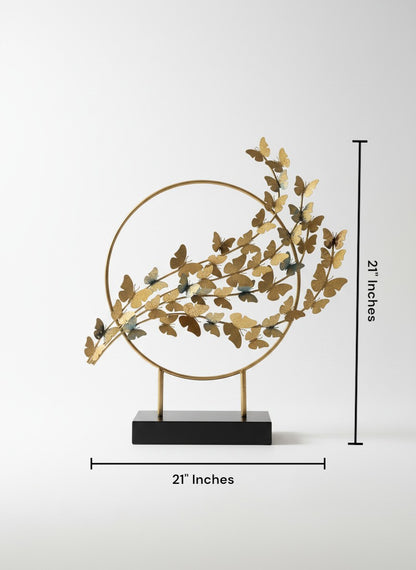 High Objects gold metal circular sculpture with numerous small butterflies in varying shades of gold and blue, mounted on a black base.