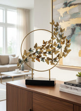 High Objects gold metal showpiece with a circular frame and a cluster of butterflies in varying sizes and shades of gold and blue.
