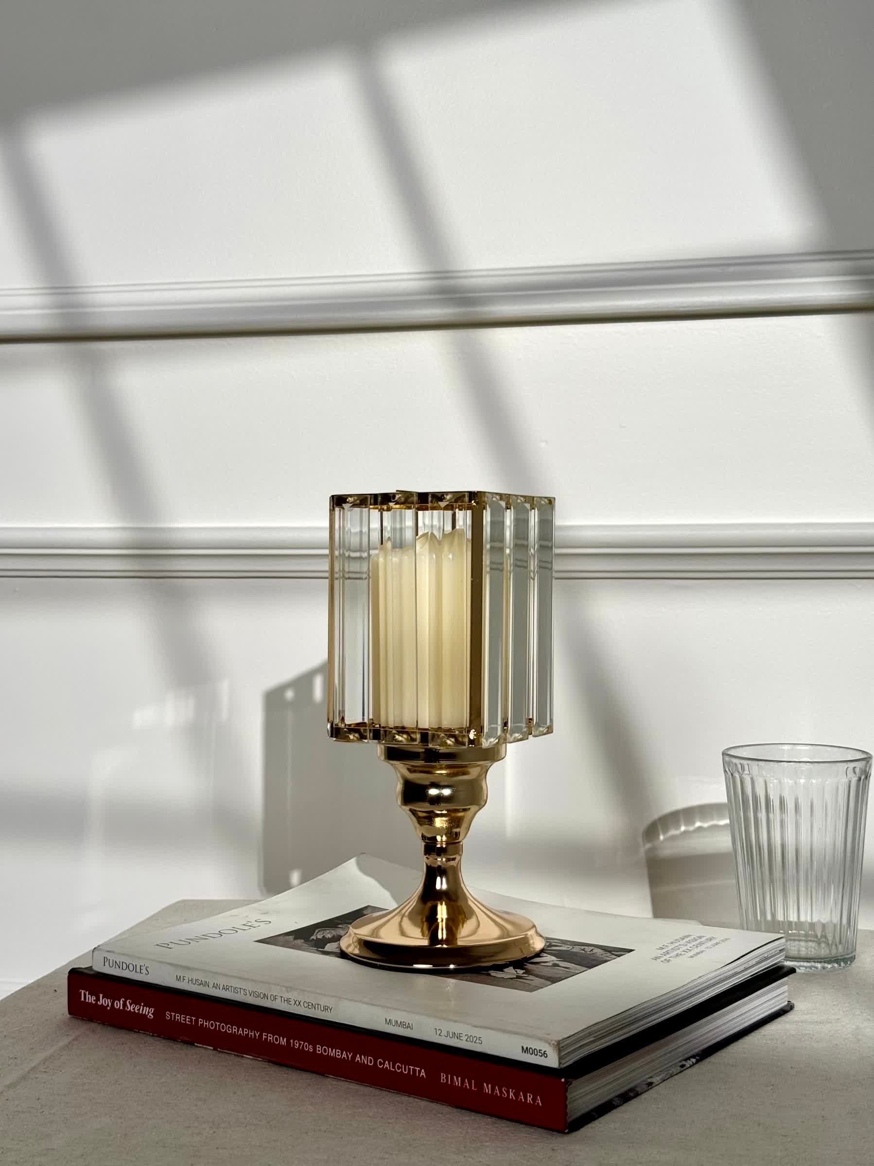 High Objects gold metal candle stand with faceted glass hurricane top and cream pillar candle.