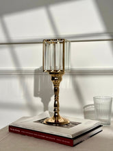 High Objects gold metal and clear glass candle stand with faceted hurricane top and pedestal base.