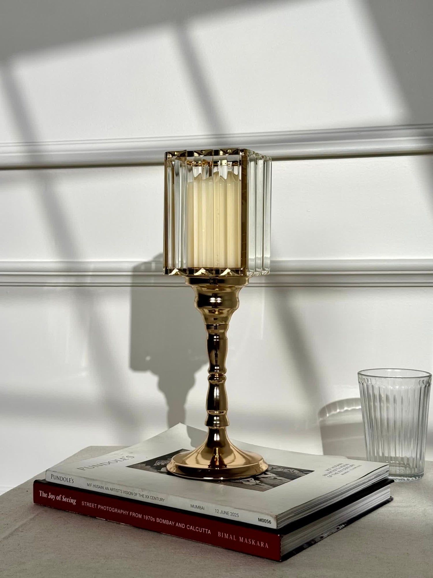 High Objects gold metal candle stand with faceted glass hurricane top and cream pillar candle.