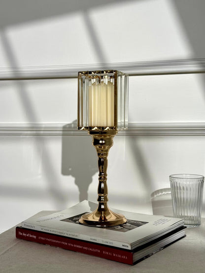 High Objects gold metal candle stand with faceted glass hurricane top and cream pillar candle.