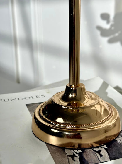 High Objects gold metal candle stand with petal-inspired base and fluted details. Elegant pedestal design.