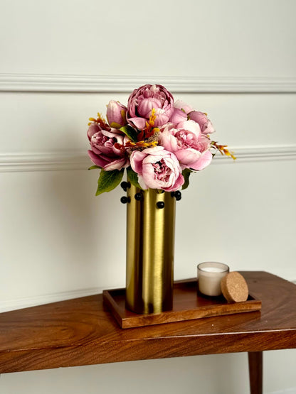 High Objects gold metal vase with rounded studs, holding pink peonies and greenery. Modern decor.
