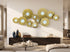 High Objects gold metal wall art featuring a cluster of textured circular discs with white centers in a modern living room