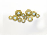 High Objects gold metal wall art featuring a cluster of textured circular discs with white centers in a modern living room